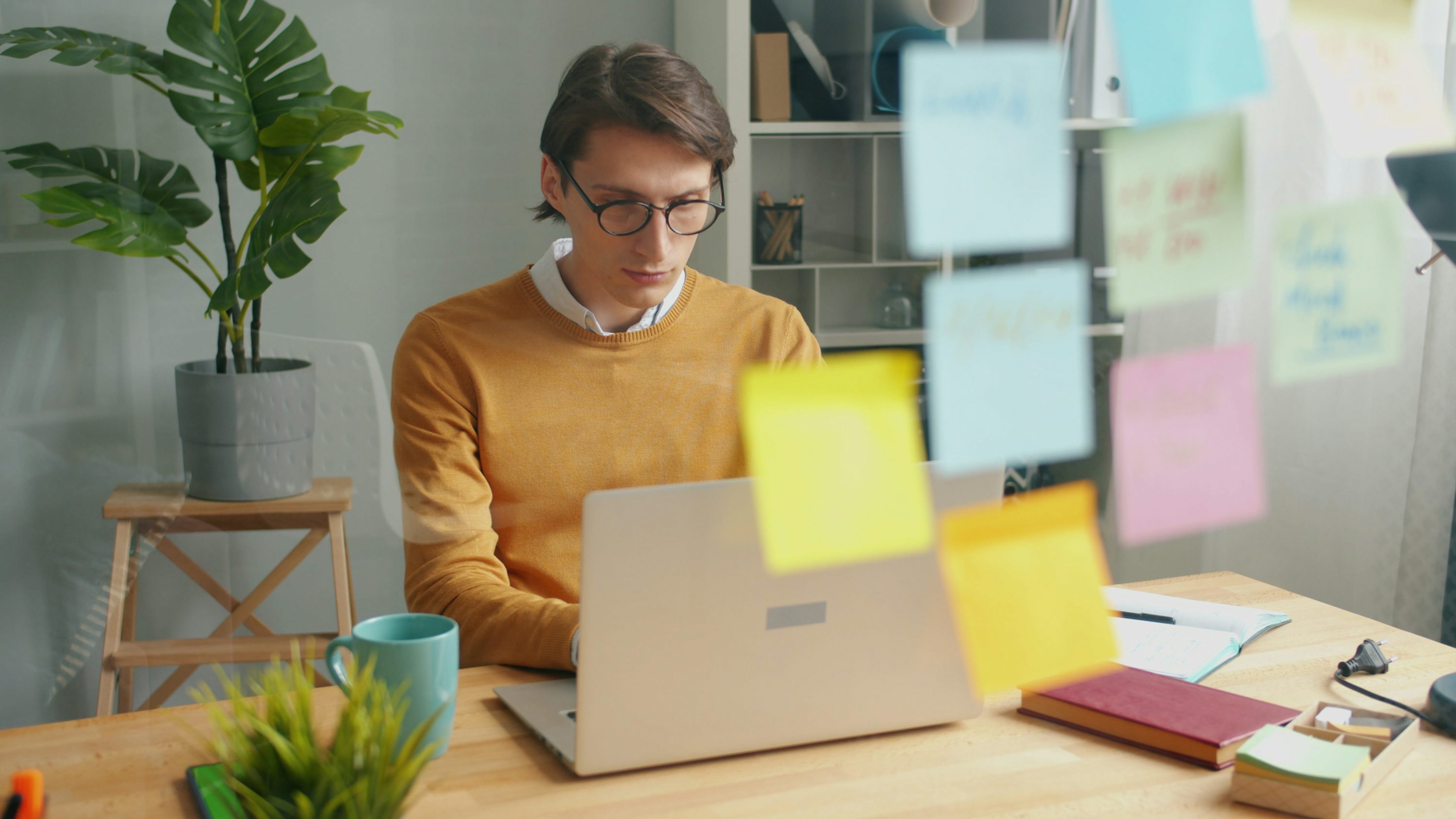 Man working on a laptop with sticky notes.