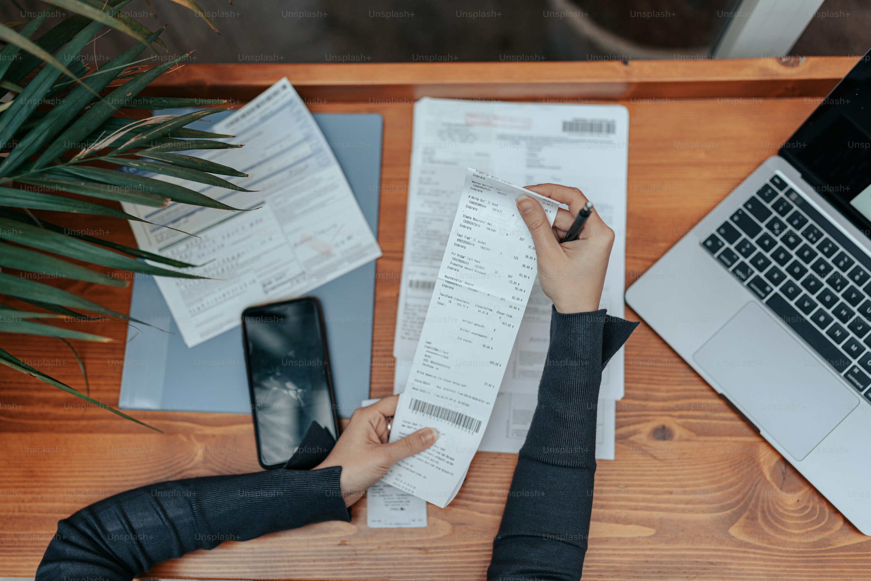 Person reviewing receipts and financial documents next to a laptop.
